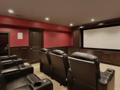 Finished residential home theater installation by AFTECHS featuring reclining theater seating, large projection screen, recessed lighting, and red accent walls